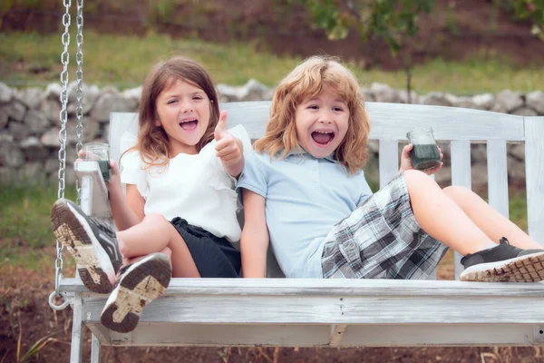 屋外で遊んでいるかわいい興奮した小さな子供たち。春の公園で2人の幸せな若い子供の肖像画。裏庭でかわいい男の子と女の子。庭を歩いている妹と弟. — ストック写真