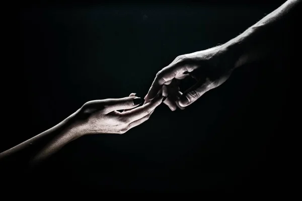 Two hands reaching toward. Tenderness, tendet touch hands in black background. Romantic touch with fingers, love. Hand creation of adam. — Stock Fotó