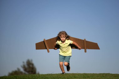 Çocuk parkta karton oyuncak kanatlarla oynuyor. Çocuk günü kavramı. Pilot kostümlü çocuk oynuyor ve havacı uzay adamı olmanın hayalini kuruyor. Çocuk özgürlüğü kavramı.