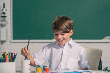 Çocuk okulda ya da anaokulunda renkli kalemlerle güzel çizim yapıyor. Çocukluk eğitimi, çocukların sanatsal becerileri..