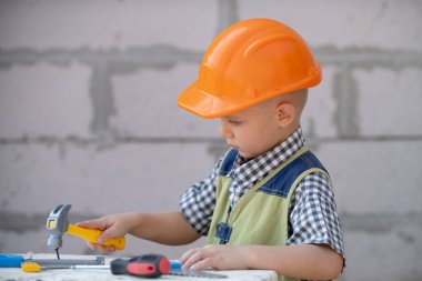 Child in helmet is construction worker. Foreman kid work in the hard hat making repairs. Childhood development. Little builder engineer. Improve your childhood.