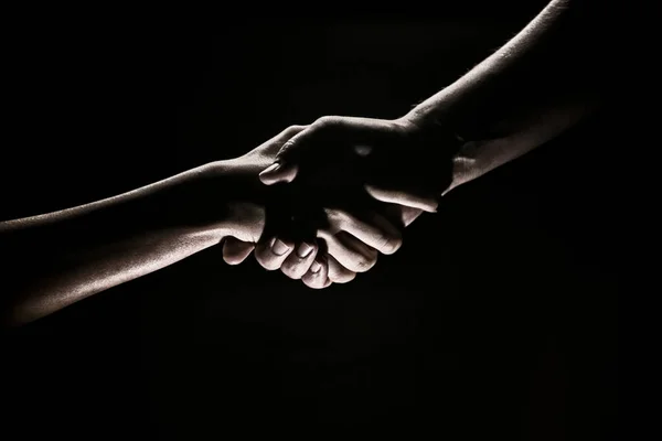 Handdruk hand, arm op redding. Sluit de helphand. Twee handen, helpende arm van een vriend, teamwork. Redding, hulp bij gebaren of handen, akkoord. Zwarte achtergrond. — Stockfoto