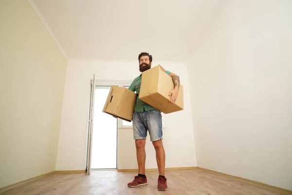 Un homme portant une boîte en carton le jour du déménagement. Livreur chargeant des boîtes en carton pour déménager dans un appartement. — Photo