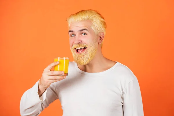 Man with orange juice on orange background. Close up portrait young man holding glass orange juice. Juicy orange. — Stock Photo, Image