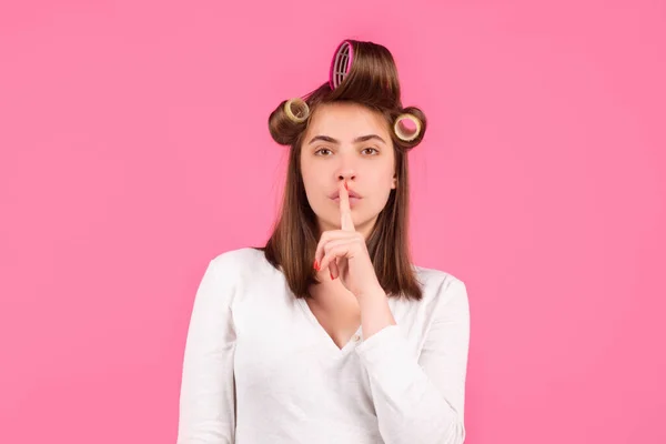 Shh, womens secrets. Woman with curlers showing secret sign. Funny housewife. Closeup portrait of young woman is showing a sign of silence with shhh. — Stock Fotó