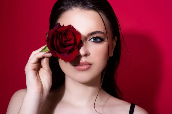布鲁内特女人蓝眼睛红玫瑰漂亮的姑娘，开了很多花。年轻美丽女子的脸，有着健康洁净的皮肤和明亮的妆容. — 图库照片