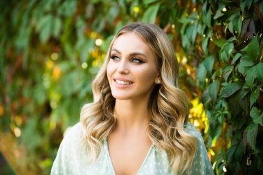 Portrait of a young woman, close up face of beautiful woman in park outdoor. Woman with romantic smile. Cheerful female model.