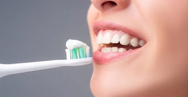 Close-up mouth with teeth-brush. Dental health care clinic. Close-up of a young woman is brushing her teeth. Toothbrush with toothpaste. Dental banner, copyspace. — Stok Foto