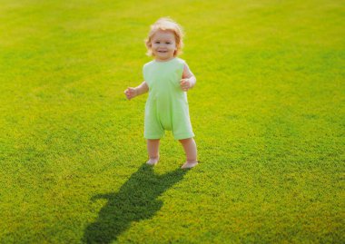 Küçük bebek çimlerin üzerinde emeklemeyi öğreniyor. Çocuk aylarını düşün. Yeşil çimlerin üzerinde oynayan mutlu çocuk. İlk adım.