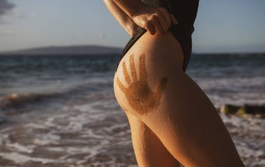 Closeup womans buttocks on sea beach. Women ass in black bikini swimsuit. Luxury butt. Sensual seductive young girl.