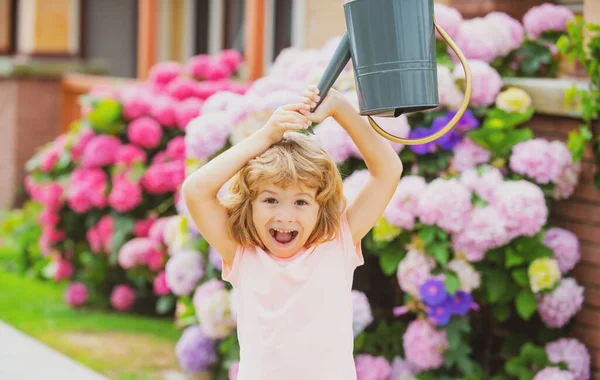 Αστείο παιδί ποτίζει λουλούδια. Το παιδί στον κήπο ποτίζει τα λουλούδια από ένα ποτιστήρι το καλοκαίρι. Παιδί κηπουρός έχει τη διασκέδαση απολαμβάνει τη φροντίδα των φυτών, περιποίηση λουλουδιών. — Φωτογραφία Αρχείου