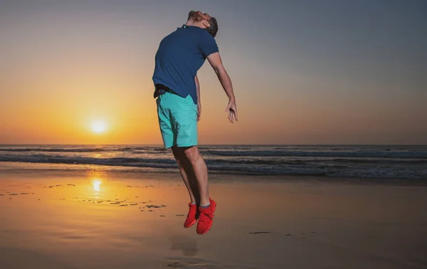 De mens springt op de natuur, silhouet in de zonsondergang. Geweldig uitzicht op zonsondergang strand. — Stockfoto