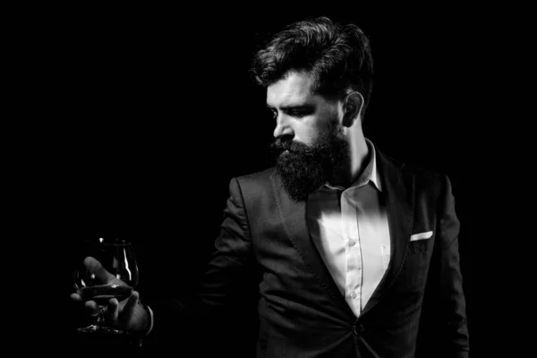 Un bell'uomo barbuto che regge un bicchiere di cognac. Degustazione e degustazione concetto. Barman o barista serve cognac. — Foto Stock