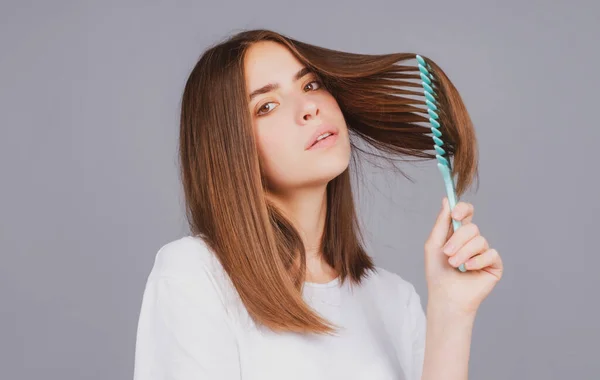 Tarakla saçlarını tarayan bir kadın. Saç fırçasıyla uzun, sağlıklı saçları tarayan bir kız. Saç bakımı güzellik konsepti. Saç fırçalama. — Stok fotoğraf