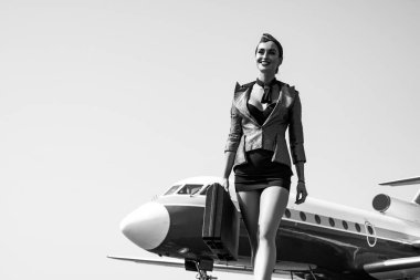 Hostes. Seyahat ve jet yolculuğu. Kadın ve ticari uçak. Mavi üniformalı çekici hostes portresi. Hostes ve seyahat zamanı. İş adamları ve ticari jet uçakları.