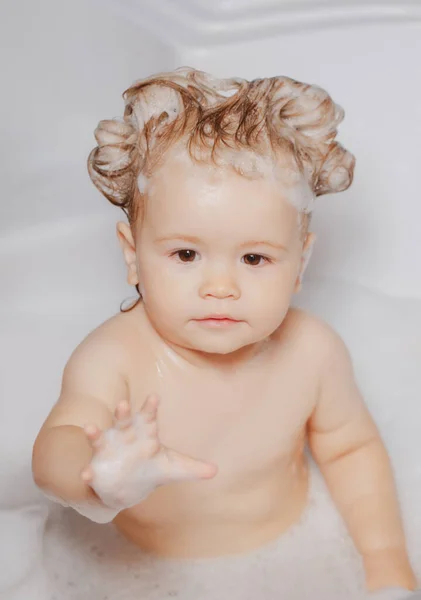 Enfant sous la douche. Bébé enfant se lave dans une salle de bain en mousse. Enfant dans la baignoire avec bulle de savon moelleux. — Photo