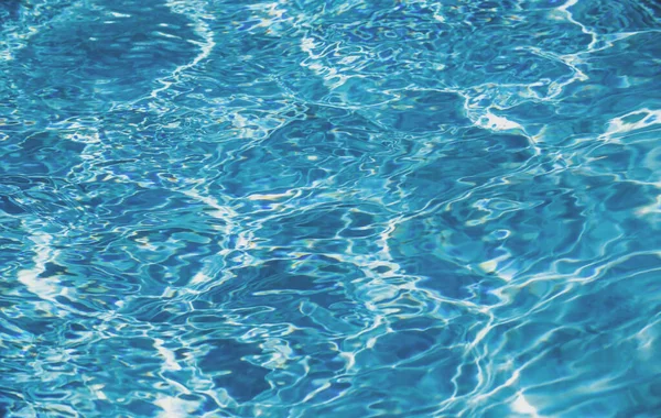 Yüzme havuzunda güneş yansımalı dalgalı su. Dalgalı su arkaplanı. — Stok fotoğraf