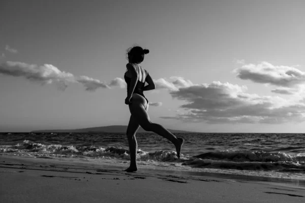 Silhouette egy fiatal nő fut végig a tengerparton a tenger. — Stock Fotó