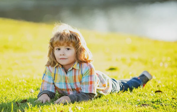 Kinder im Freien. Kinder im Park. Spring Boy im Gras liegend. Sommerspaziergang. Anpassung der Kinder. — Stockfoto