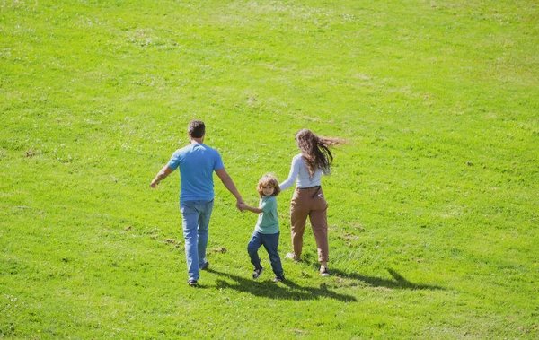 Back view of happy young family spending time together outside in green nature. — Stock Photo, Image