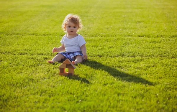 Försäkringsbarn. Baby spela i grönt gräs. Varm vår i parken. — Stockfoto