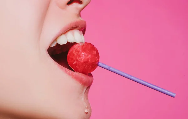 Ağzında kırmızı lolipop şekeri tutan pembe rujlu yakın plan kadın dudakları. Lolipop dudaklı kadın yüzü. — Stok fotoğraf