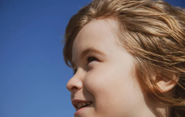 Porträt eines kleinen Jungen, der wegschaut in den blauen Himmel mit Kopierraum, Gesicht aus nächster Nähe. Kopf schießt auf Kinderporträt. — Stockfoto