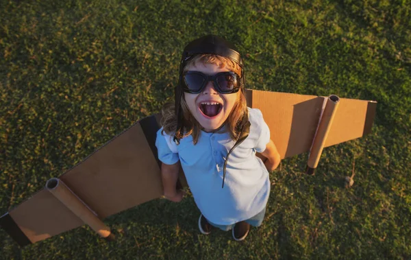 Criança engraçada brincando com jetpack de brinquedo. Criança astronauta piloto ou astronauta sonhos de voo. Aviador voando com asas de papelão. — Fotografia de Stock