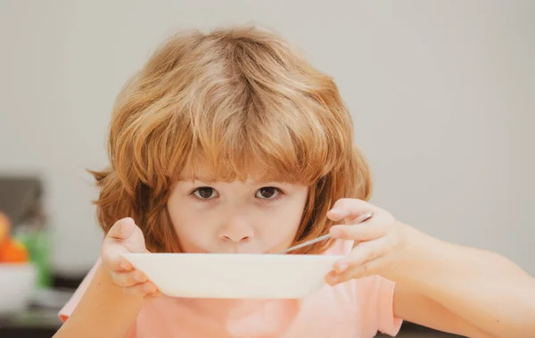 Barn äter. Lite frisk hungrig pojke äter soppa med sked. Söt nyfiken hungrig rolig unge. — Stockfoto