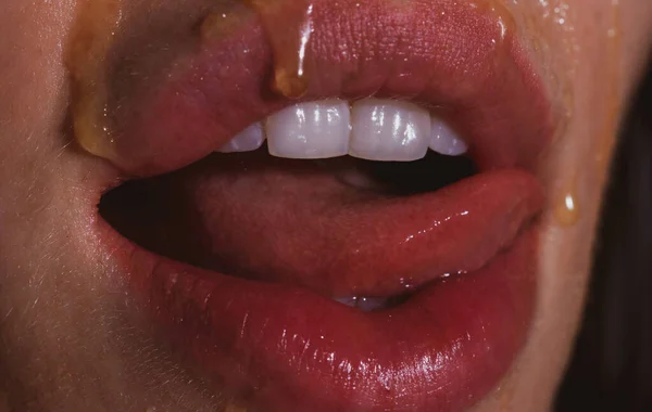 Sexy volle Lippen. Honig tropft auf sexy Mädchenlippen. Honig essen. Konzept für gesunde Ernährung. — Stockfoto