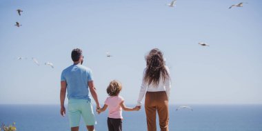 Mutlu aile tatilleri. Neşeli baba, anne, bebek kumsalda yürüyor. Aktif ebeveynler ve insanlar yaz tatillerinde çocuklarla birlikte dışarıda etkinlik yapıyorlar. Çocukluk ve ebeveynlik kavramı.