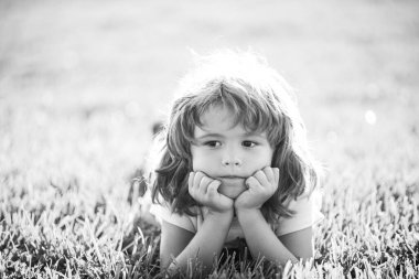 Parktaki çocuk. Çocuk dışarıda. Yay Çocuk çimlerin üzerinde yatıyor. Yaz yürüyüşü. Çocuk adaptasyonu.