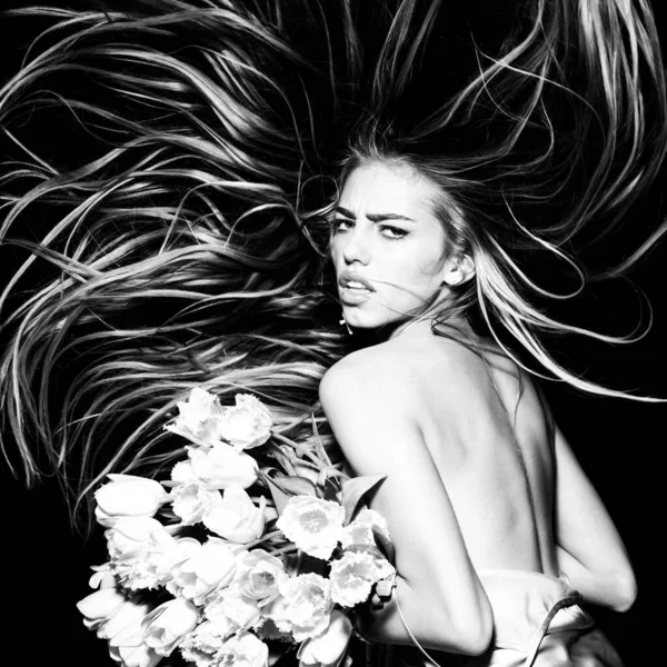 Мода молода красива жінка з тюлевим волоссям тримає квіти тюльпанів. Салон краси. Весняна зачіска. Довге волосся рухається. Модна зачіска, модна зачіска . — стокове фото