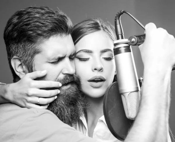 Zpěváci zpívají rock. Zvuková producentka nahrává písničku v hudebním studiu. Sexy muž a žena zpívající s hudebním mikrofonem. — Stock fotografie