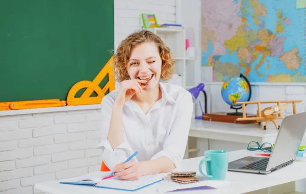 Retrato de una joven profesora o estudiante caucásica comiendo chocolate. Profesor alegre en la lección. Enseñanza. —  Fotos de Stock