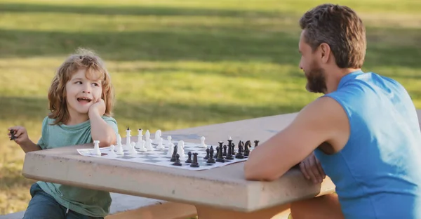 Boldog család kint. Apa és fia sakkoznak a nyári kertben. Játékok és tevékenységek gyermekek számára. — Stock Fotó