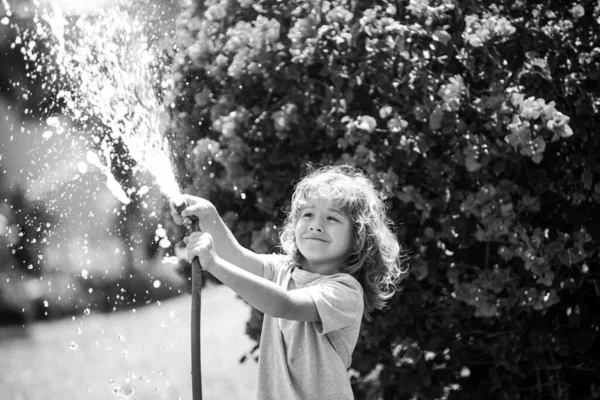 Діти грають з водяним садовим шлангом на подвір'ї. На відкритому повітрі діти літні розваги. Маленький хлопчик грає з водяним шлангом на задньому дворі. Партійна гра для дітей. Здорова активність для спекотного сонячного дня . — стокове фото