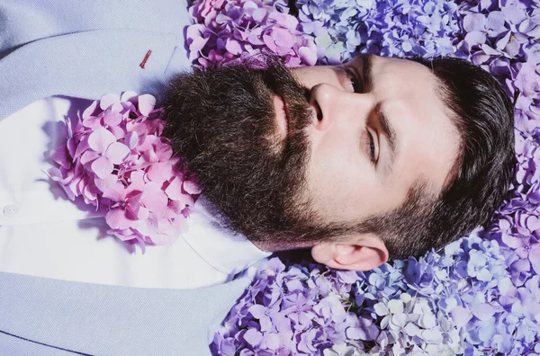 A bearded man with a decorated beard for the Spring holiday. Flower in the beard. Bearded man with beard in flover in beard, bearded gay. — Stock Photo, Image