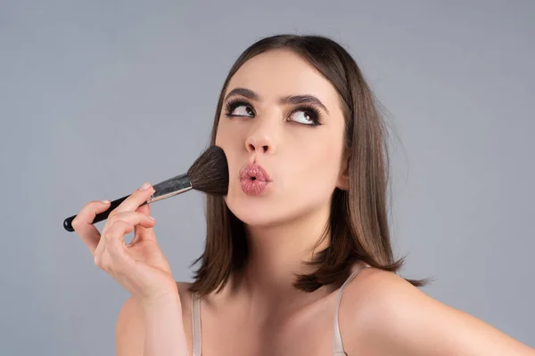 Porträtt av en rolig vacker ung flicka med makeup rouge borste, ljusa make-up. — Stockfoto