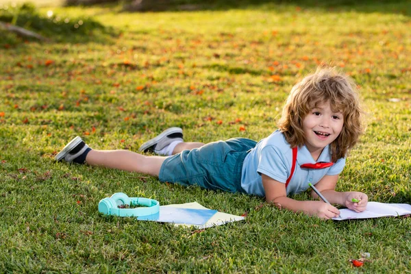 Child in park outdoor. Spring kid lying on grass. Summer boy walk. Warm summer day during school holidays. Kid boy dreaming and smiling. Cute little child on the meadow in backyard. — Photo