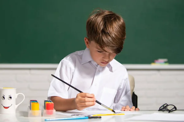 Aranyos kis gyerekrajz az osztályteremben. Portré iskolás fiúról, aki művészetet és kézműves leckét tanul az iskolában. Gyerekkori tanulás, gyerekek művészeti készségei. — Stock Fotó