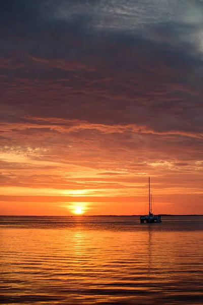 Tropisk strand med glatt bølge og solnedgangens abstrakte bakgrunn. Solnedgang med stor gul sol under havoverflaten. Rolig hav med solnedgang himmel og sol gjennom skyene over. – stockfoto