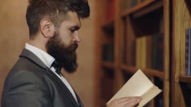 Konsantre profesör. Klasik takım elbiseli sakallı adam kütüphanede kitap okudu. Klasik edebiyat. Kitaplıkta kitap okuyan adam. İngiliz klasiği. Adam kütüphanede kitap seçiyor..