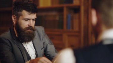 Bilim adamları konuşuyor. Profesör ve öğrenci kütüphanede tartışıyorlar. Klasik kütüphane dolabında kitap okuyan adam. Ev kütüphanesi. İş adamı klasik bir iç mekanda oturuyor, elinde kitap tutuyor..