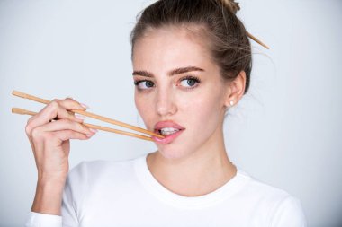 Yemek çubukları seksi dudakların yanında. Yemek çubuklarıyla dudak karıştıran güzel bir kız. Sushi reklamı için seksi bir ağız. Çin yemeği mi Japon yemeği mi?.