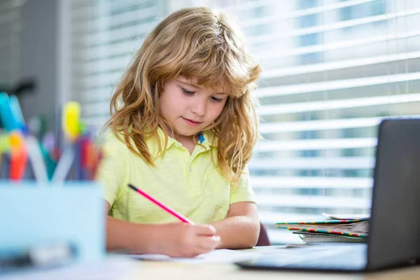 Schrijven van kinderen op school. Leuke leerlingen die schrijven aan een bureau in de klas op school. Leuke jongen die huiswerk maakt, schrijft en schildert. Kleuterjongen met boeken thuis. — Stockfoto