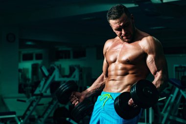 Spor salonunda pazı kaldıran bir sporcu. Spor salonunda egzersiz yapan kaslı bir adam. Güçlü erkek, çıplak karın kasları..