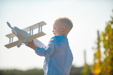 Summer at countryside. Kid dreaming and plays with a toy plane in the park. Dreams of travel. Development, growth, dreams and plans. Imagination and dream concept.
