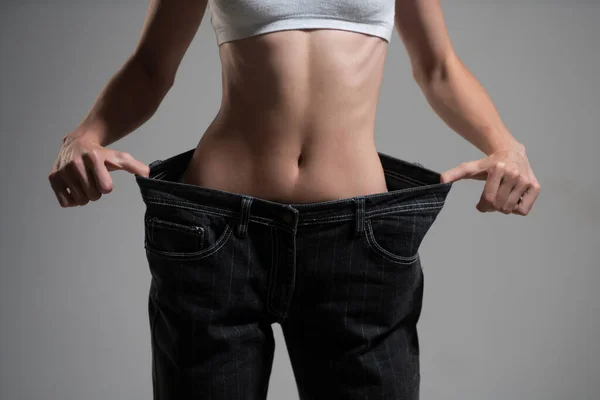 Cintura fina. Calças de mulher de grandes dimensões calças no conceito de perda de peso. Mulher em dieta conceito com jeans grandes. — Fotografia de Stock