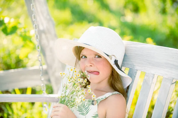Bahar çocukları portresi, komik surat. Küçük kız yeşil arka bahçedeki çiçekleri kokluyor. Yaz otlağındaki sevimli çocuk ve çiçek kokusu.. — Stok fotoğraf
